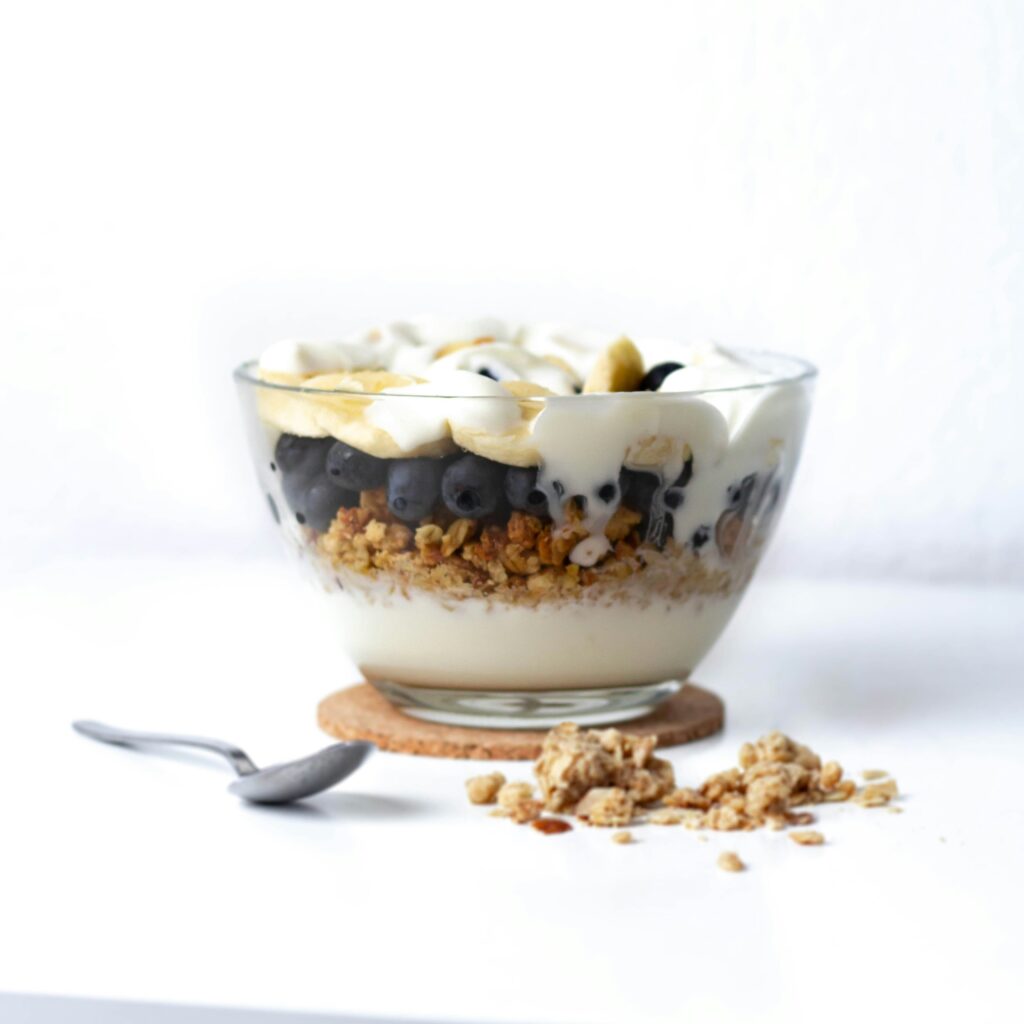 bowl filled with yogurt, granola and blueberries with a spoon on the side
